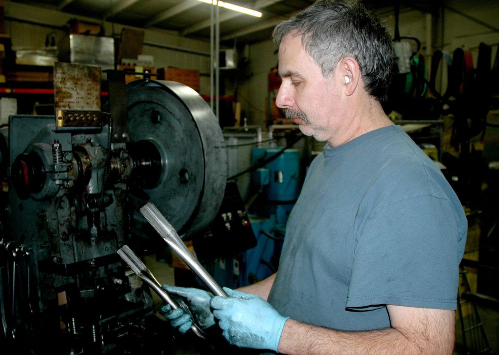  Machinist examines bent and flattened steel tubing